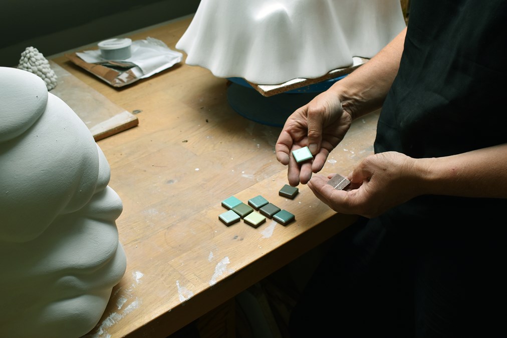 Jennifer Forsberg håller fram mosaik i olika gröna nyanser.