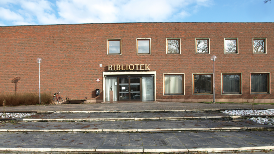 Tegelbyggnad i rött och med texten bibliotek över entrén