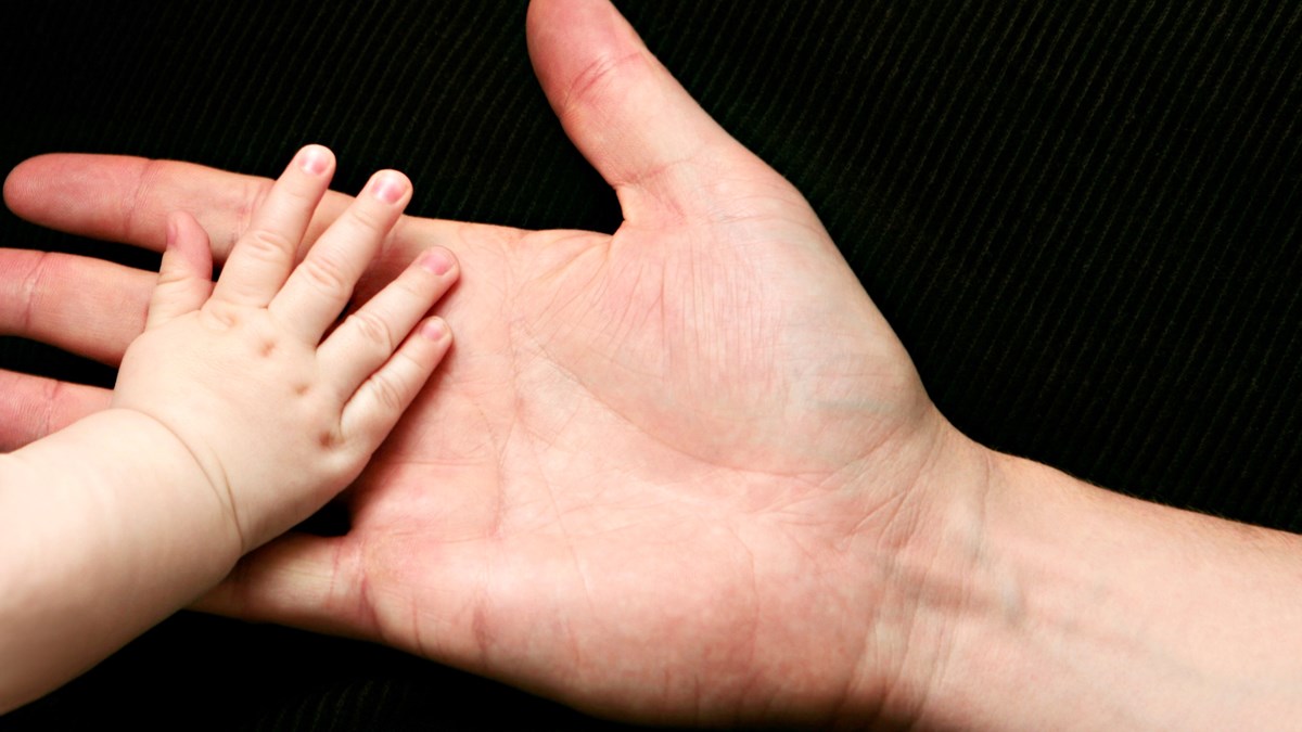 Barnhand som läggs i en vuxen hand.
