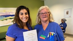 Två leende vårdpersonal håller diplom för Årets strokeenhet.