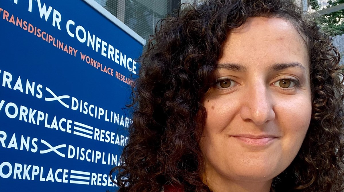 Kvinnas ansikte framför en skylt om konferens