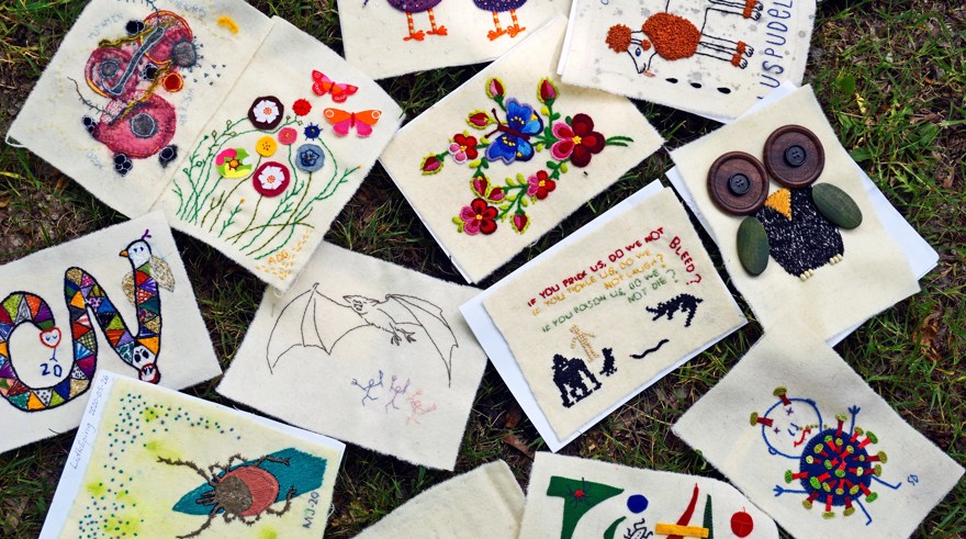 Tyglappar med broderade djur och odjur utspridda på en gräsmatta