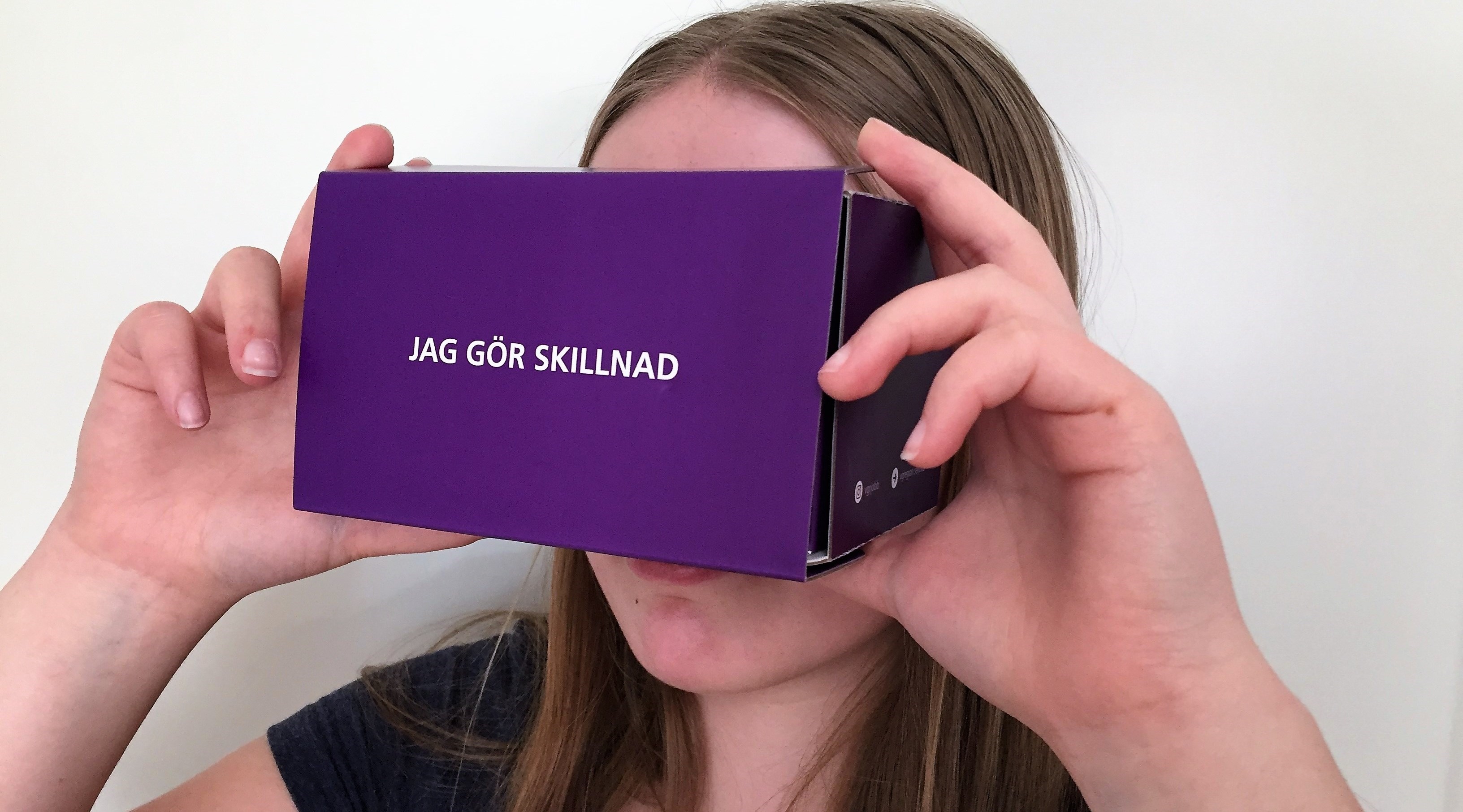 Flicka med VR-glasögon av kartong.
