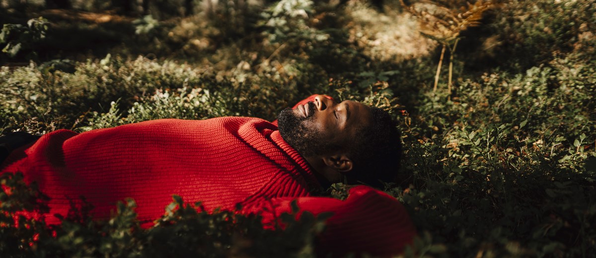 Person i röd tröja ligger ner i en skog