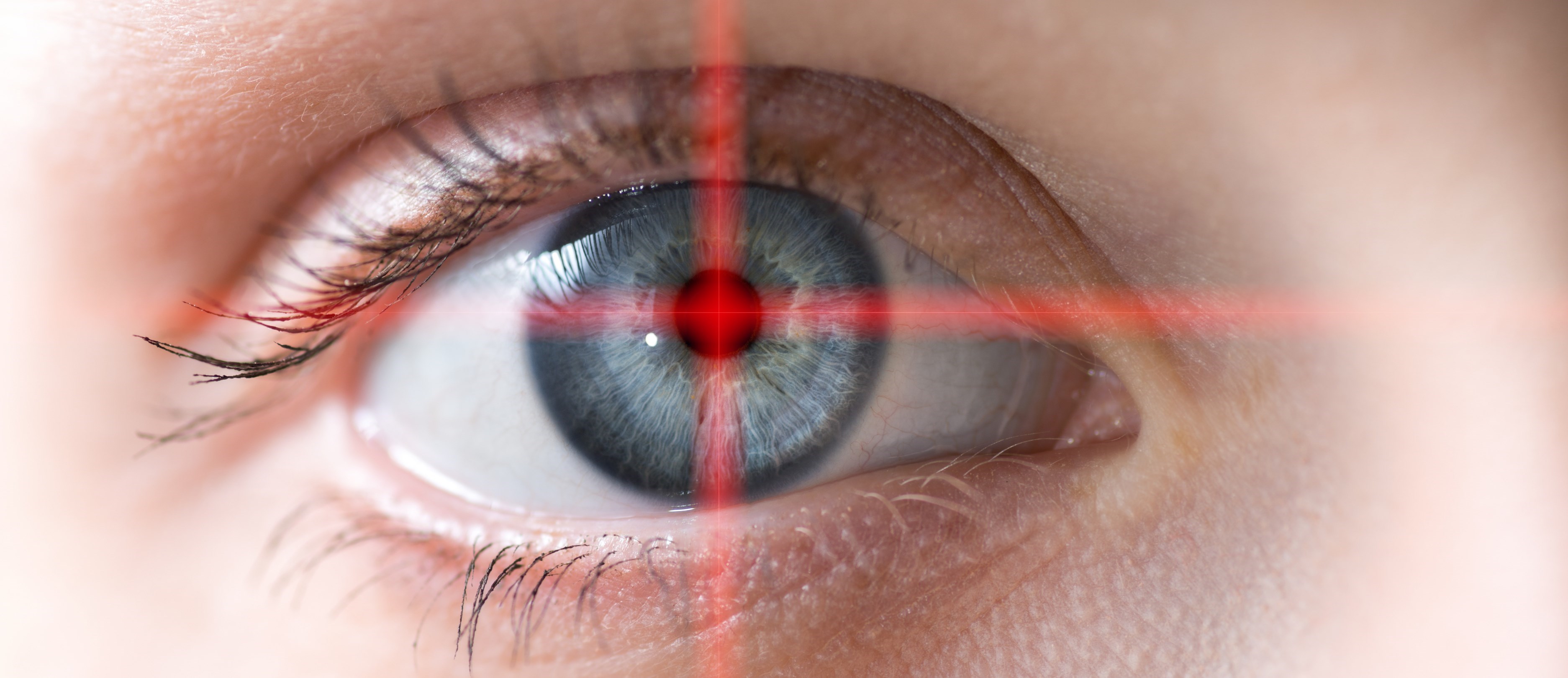 Närbild på ett öga. Från pupillen sprider sig ett rött kryss som fortsätter ut över hela bilden.