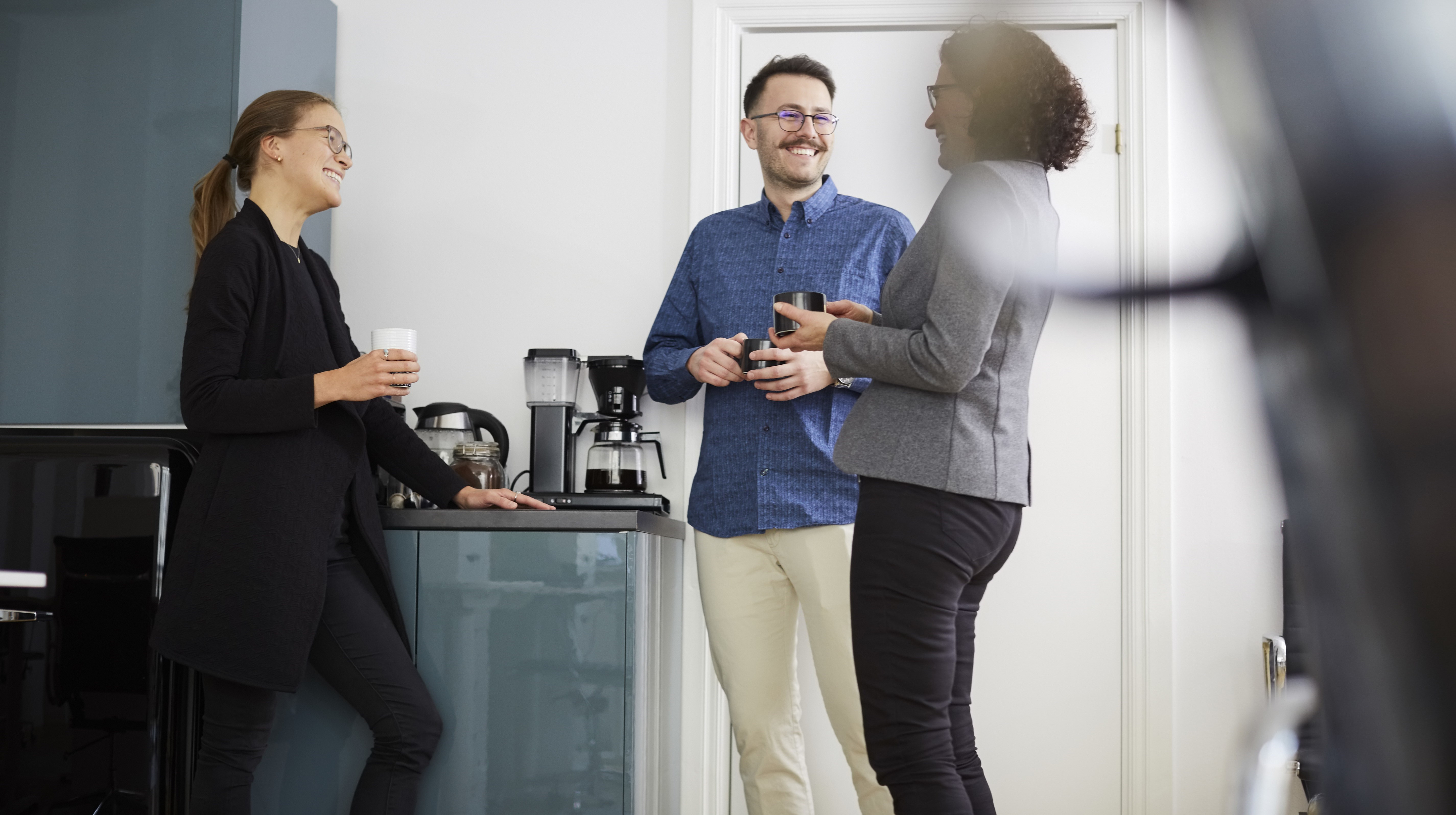 Kollegor pratar och skrattar vid kaffemaskinen