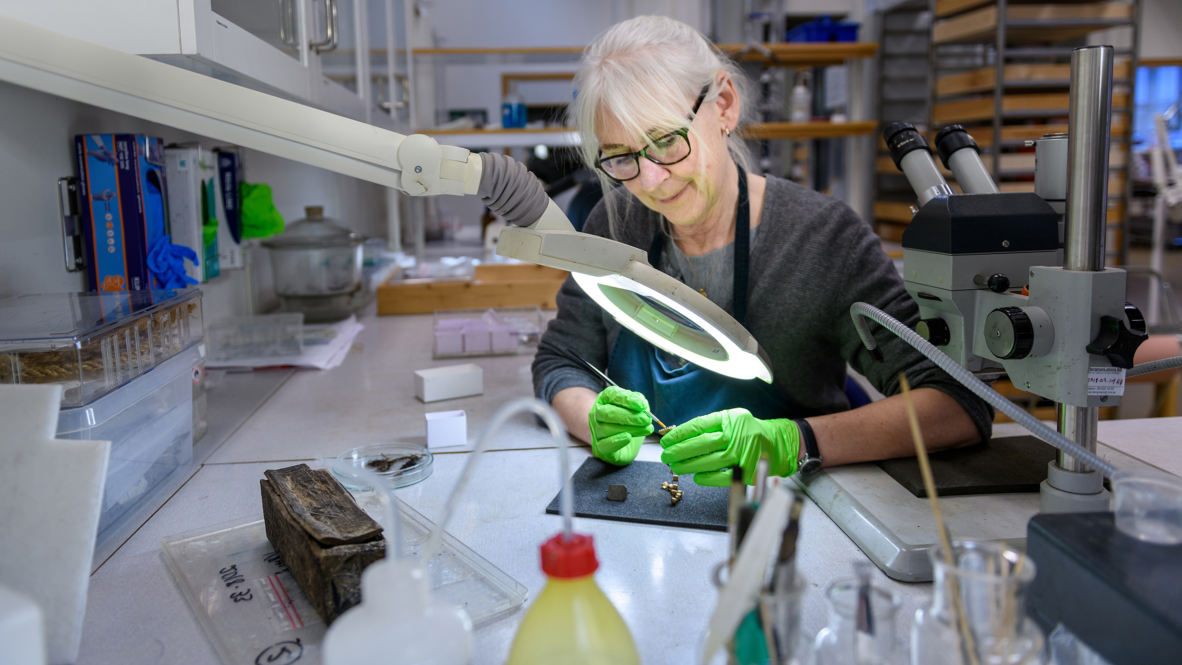 En arkeologikonservator i sitt arbete med ett träskrin.