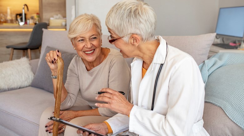 Äldre kvinnlikdoktror sitter tillsammans med kvinnlig patient