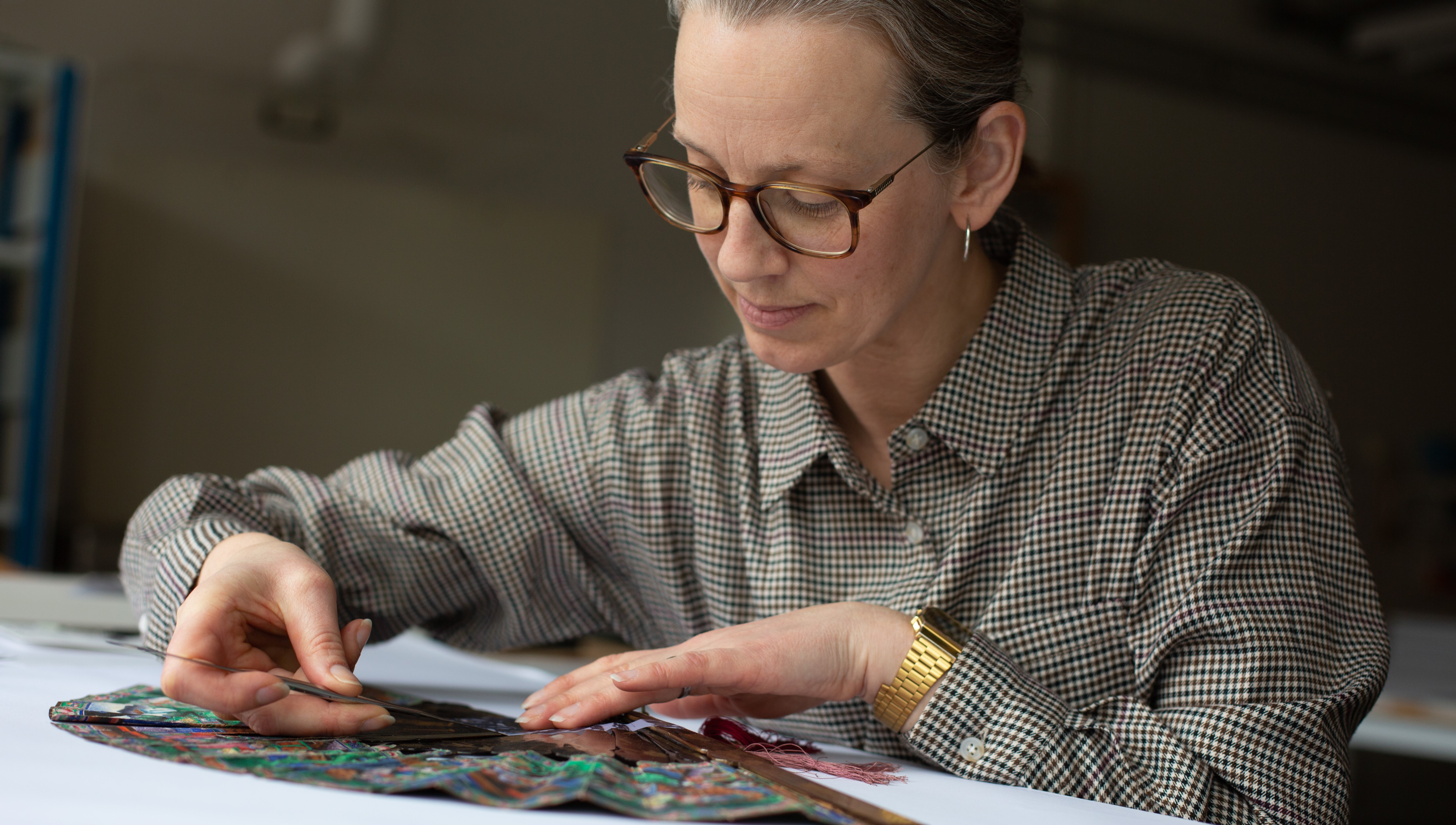 En person arbetar med pincett på en solfjäder under stor koncentration.