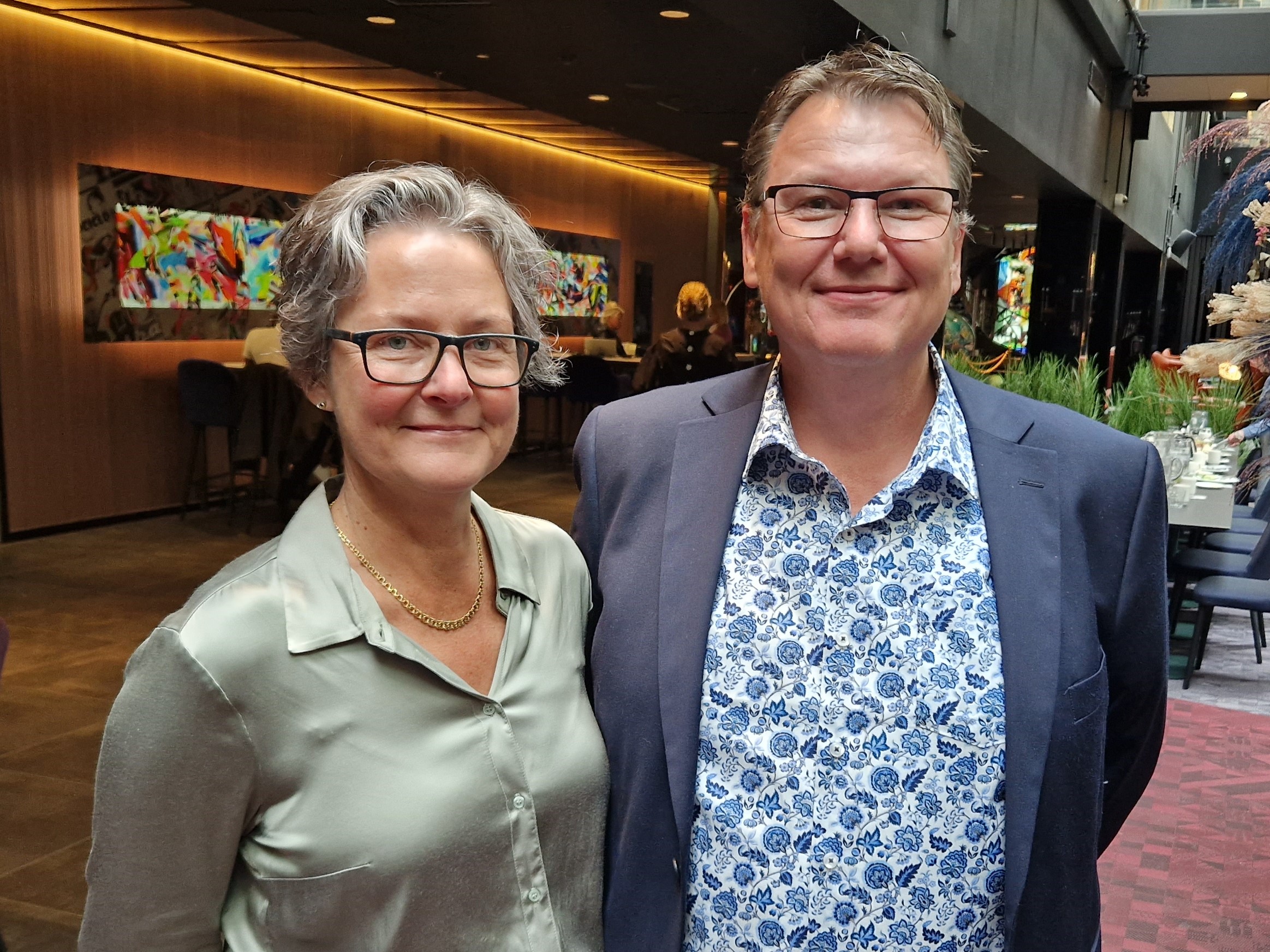 En kvinna och en man står i konferensmiljö