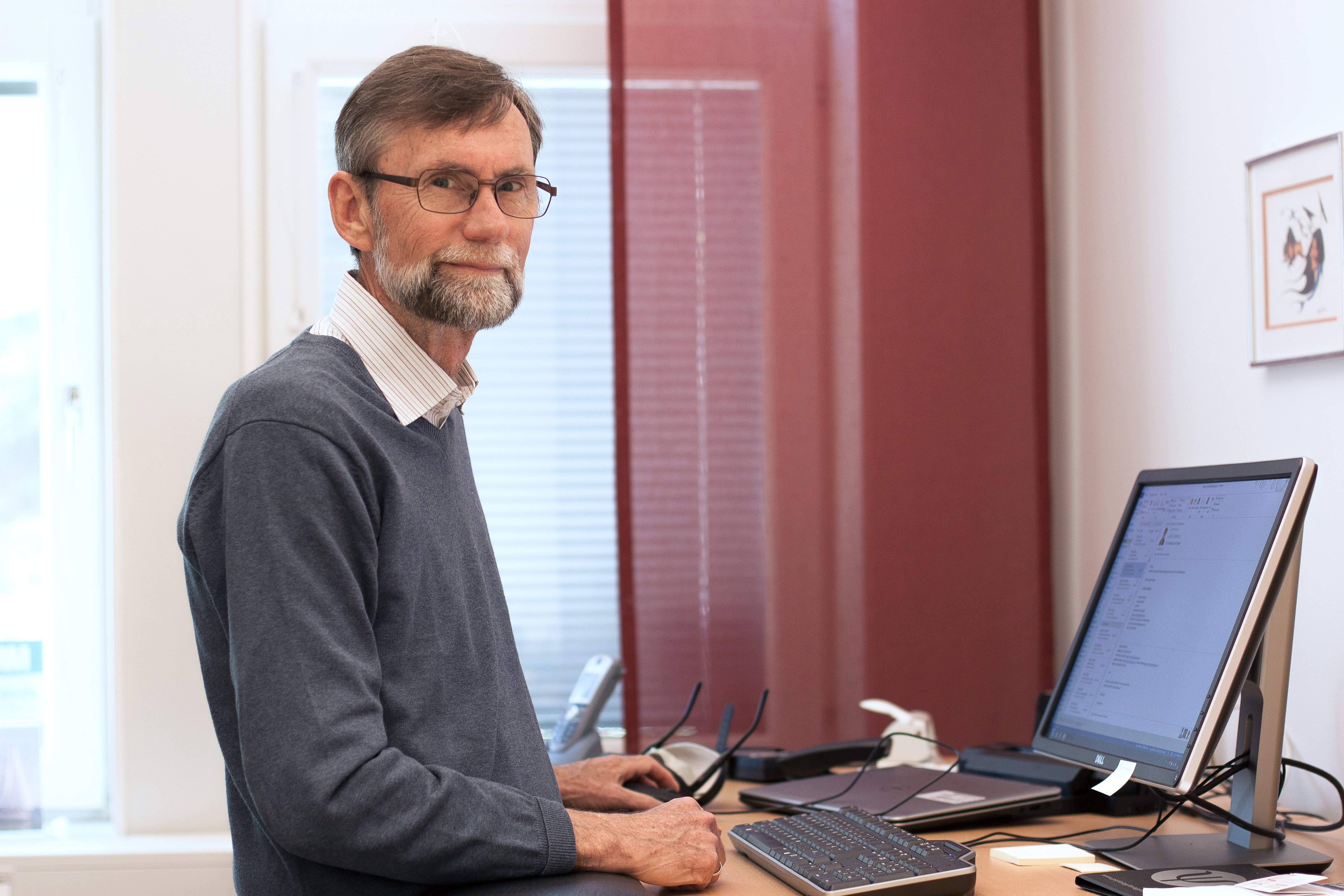 man står vid skrivbord och tittar mot kameran