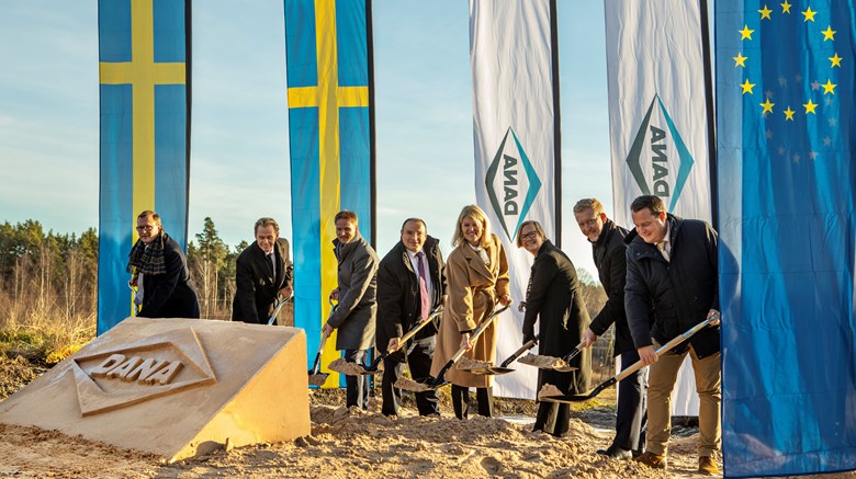 Flera personer ta officiella spadtag med flaggor i bakgrunden för etablering av fabrik i Åmål