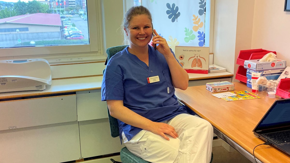 Frida Strömberg-Celind sitter och talar i telefon i mottagningsrum. Hon ler och ser välkomnande ut.