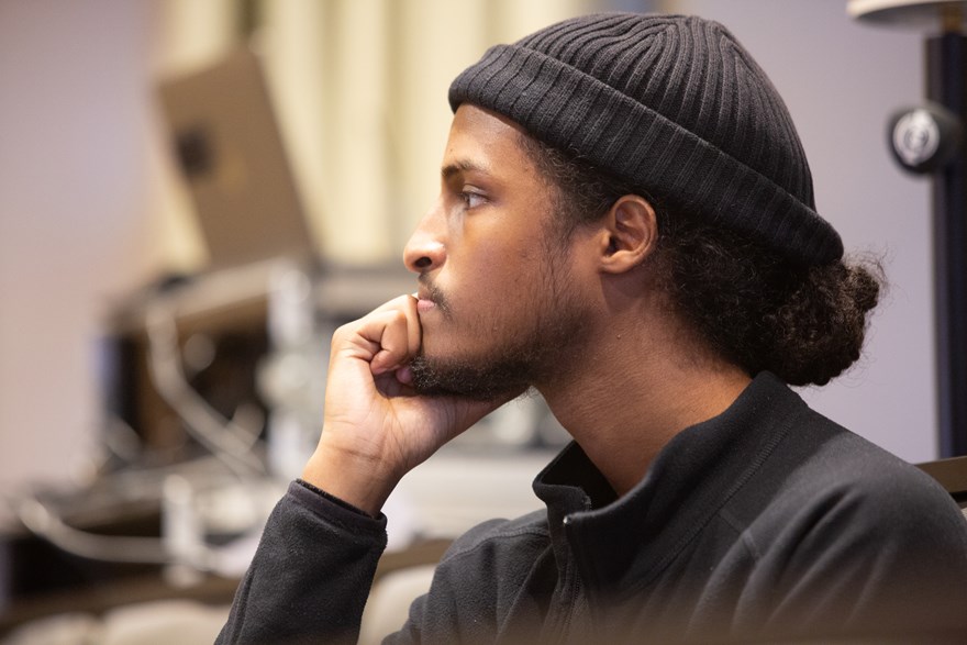 En ung man med svart mössa tittar fokuserat mot någonting utanför bilden.