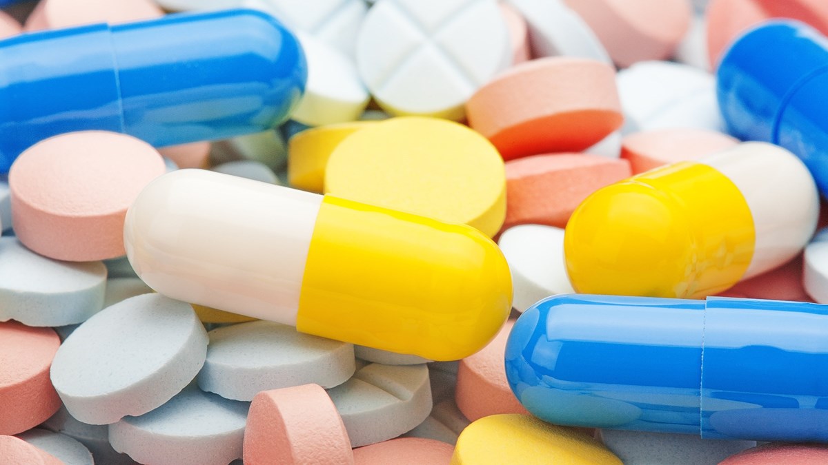 Närbild av många tabletter och piller i olika färger.