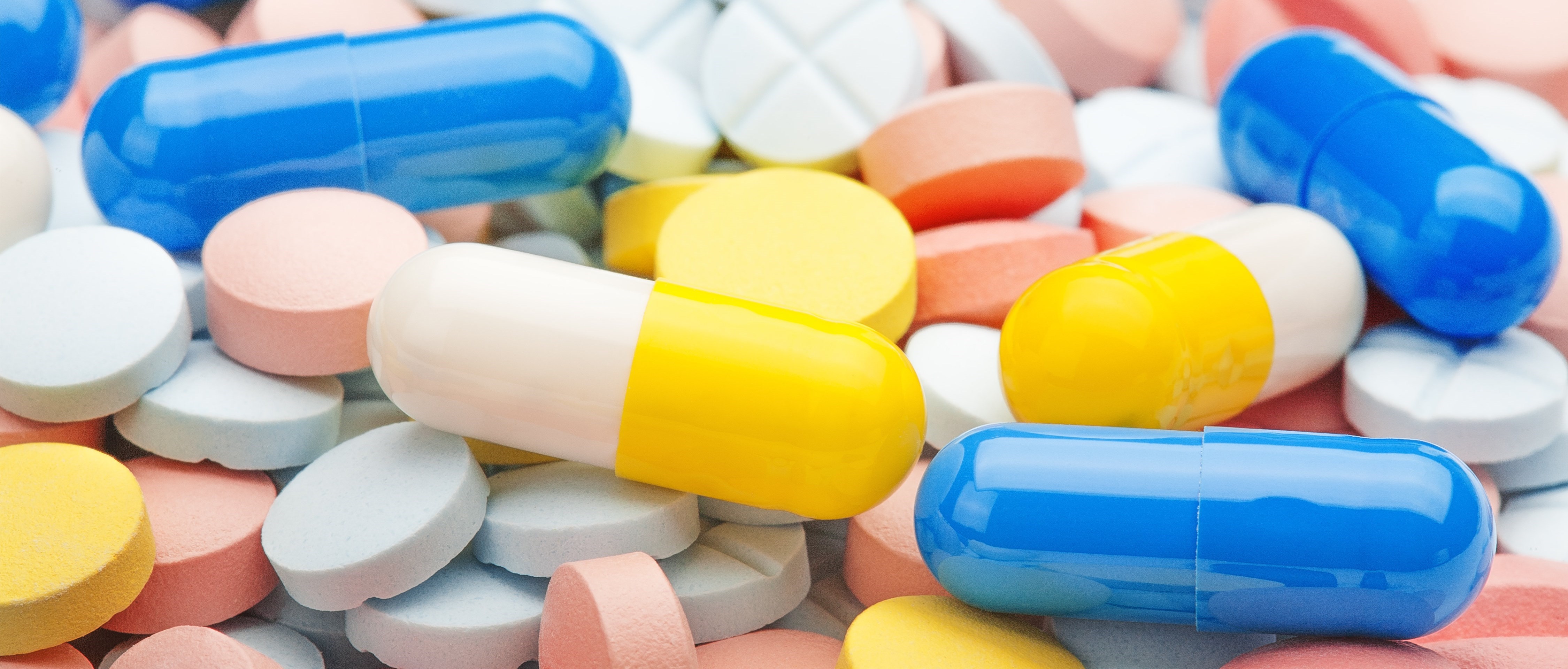 Närbild av många tabletter och piller i olika färger.