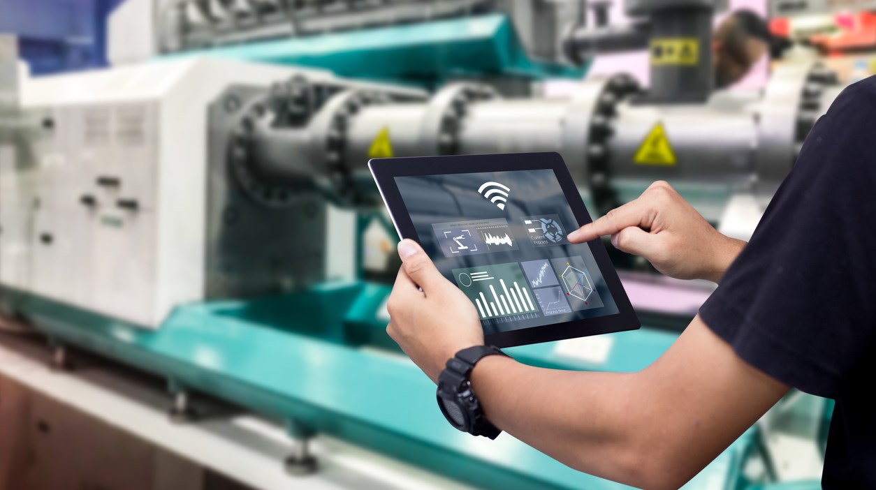 Hands holding tablet on blurred automation machine as background