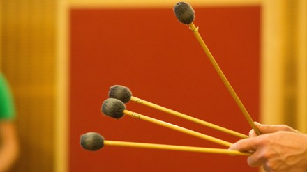 Två händer som håller fyra trumklubbor.