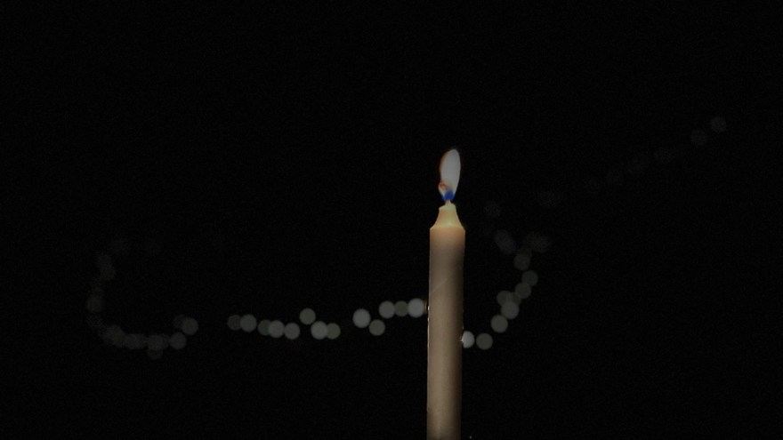 Ett levande ljus står på ett bord med ljusslinga