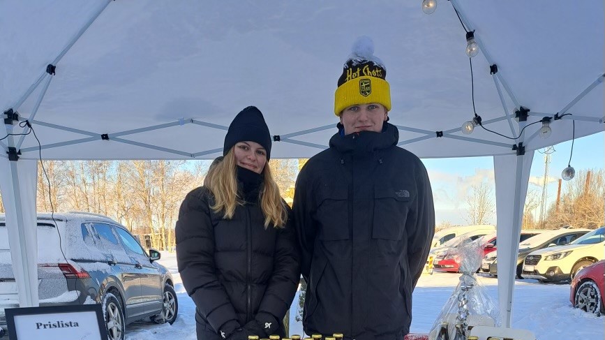 Två elever visar upp sina produkter på ett bord