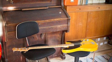 En tramporgel och en gul elbas som ligger på en stol. I bakgrunden syns en bokhylla.
