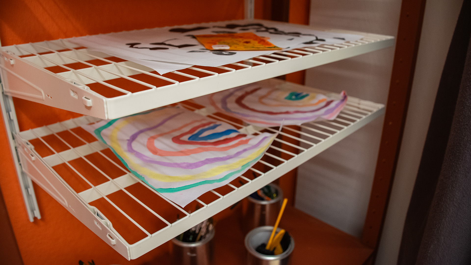 Teckningar ligger på tork. Två av dem föreställer regnbågar. 