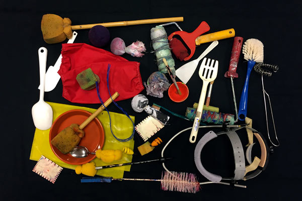 En samling köksredskap och målarredskap ligger på en svart bakgrund