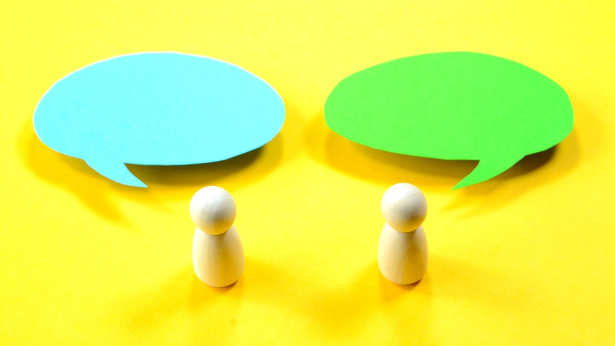 Two wooden human figures communicating with speech bubbles on yellow background