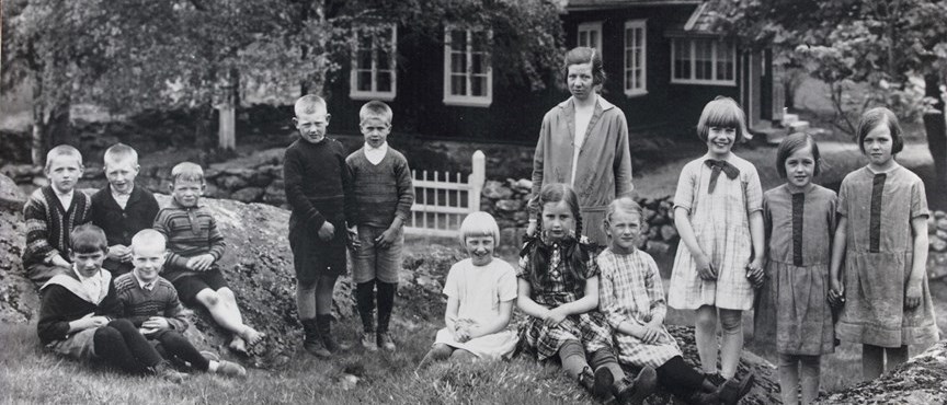 En svartvit bild av flera barn som tittar in i kameran. 