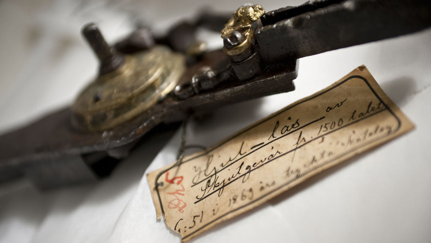 Ett metallföremål som är försett med en äldre handskriven lapp.