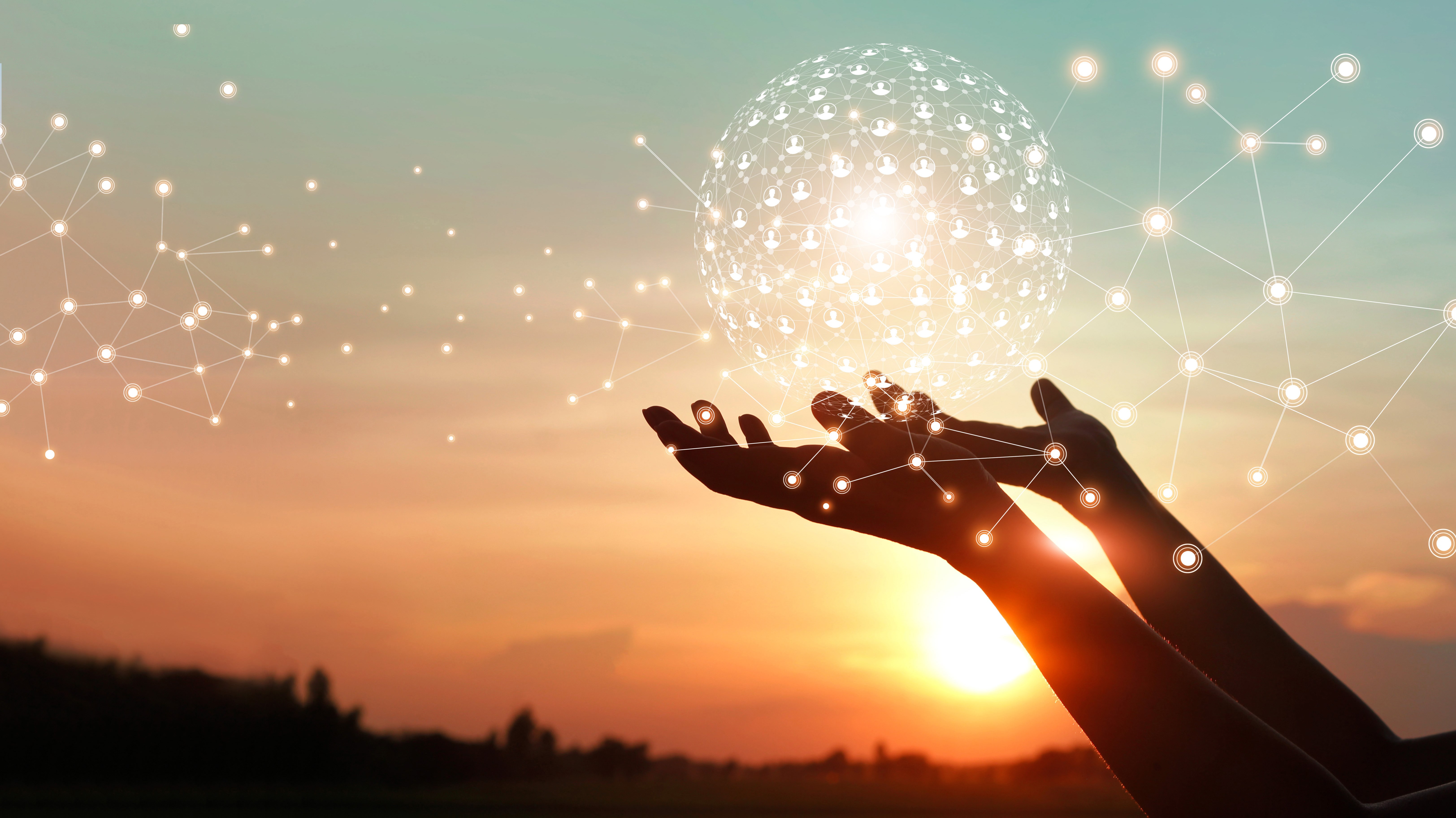 Två händer håller i ett transparent klot med solnedgång i bakgrunden