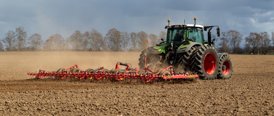 Traktor med dubbelmontage harvar på öppet fält