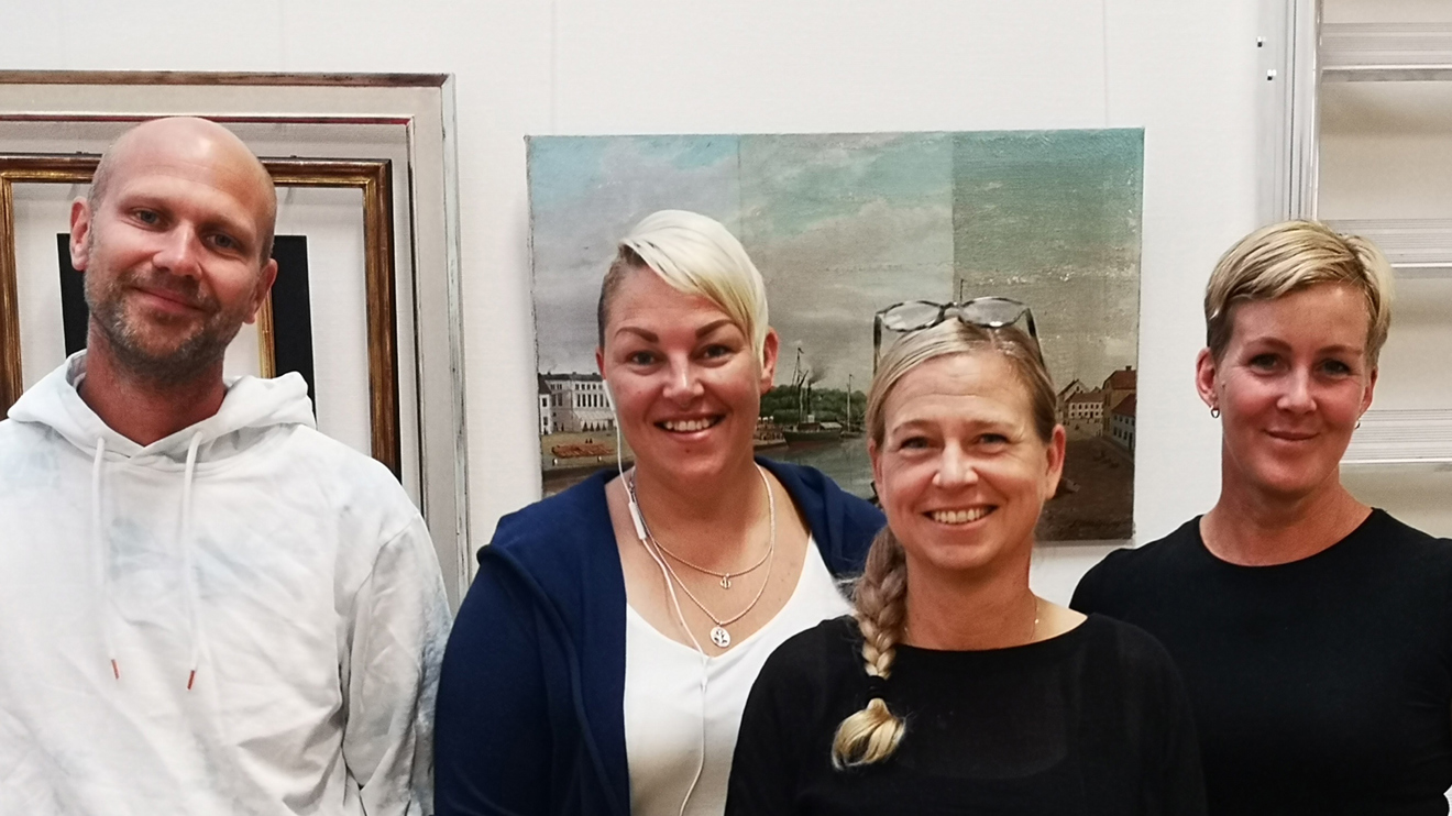 Fyra glada människor tittar in i kameran.