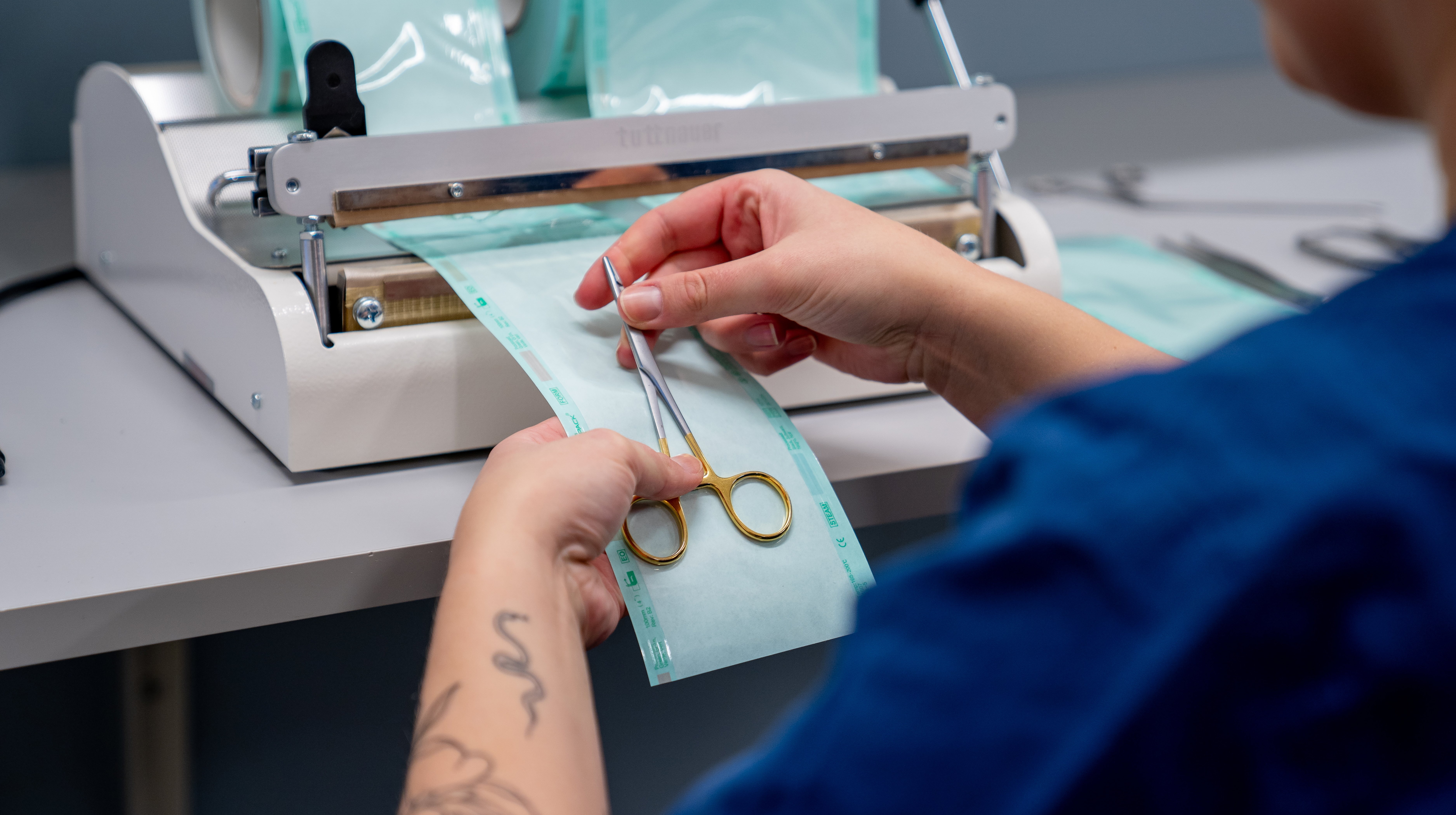 Händer håller i en sax framför en maskin med pappersremsa