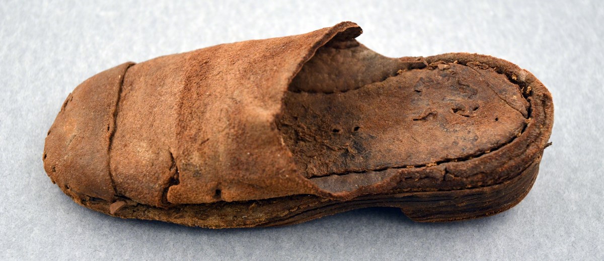 Bilden visar en liten, sliten brun lädertoffel.