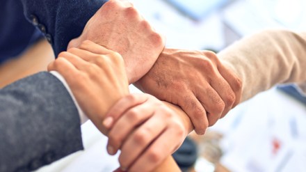 Fyra händer som håller i varandras vrister och bildar en fyrkant.