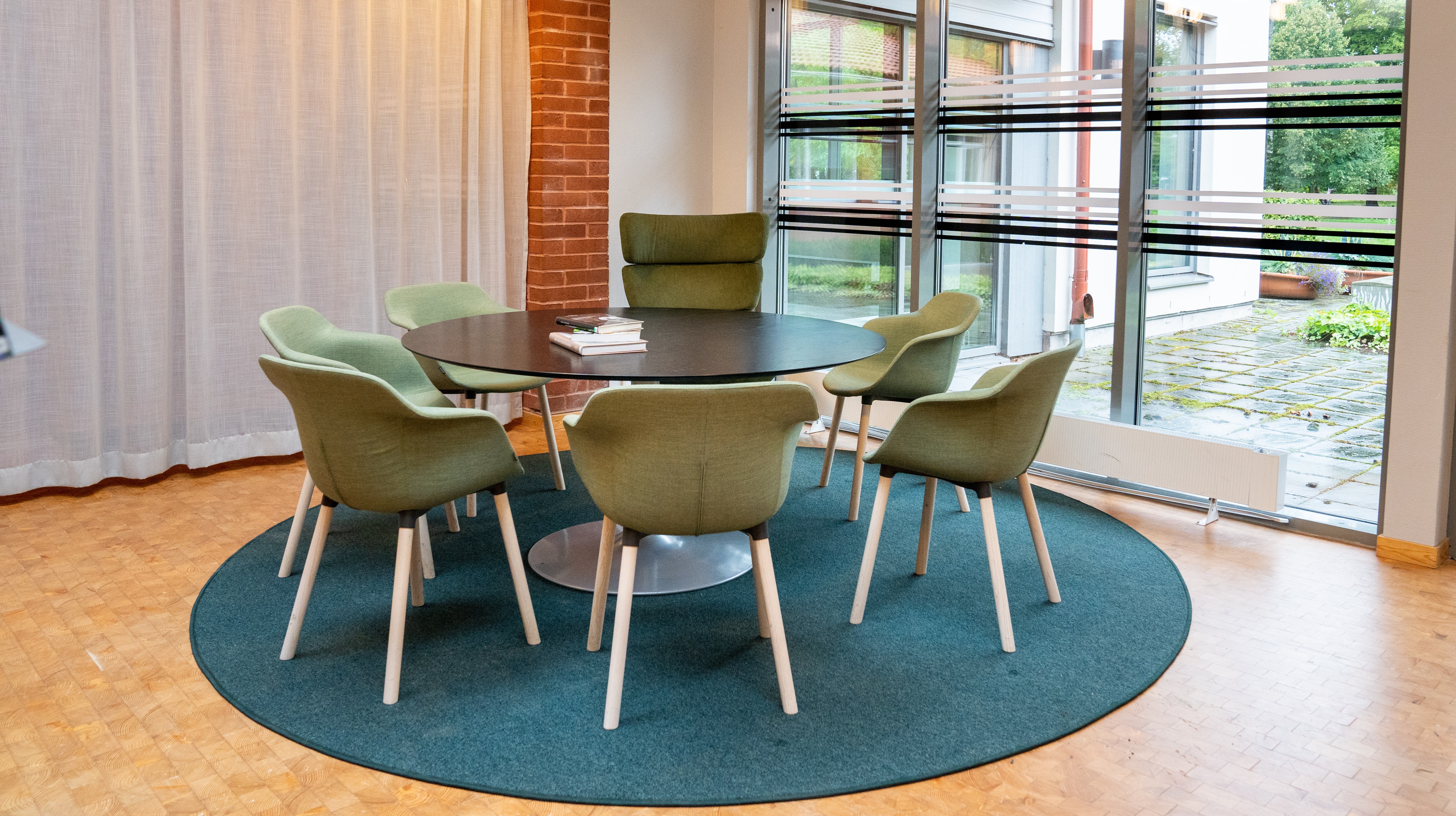 Bord med gröna stolar framför  stort fönster i biblioteket