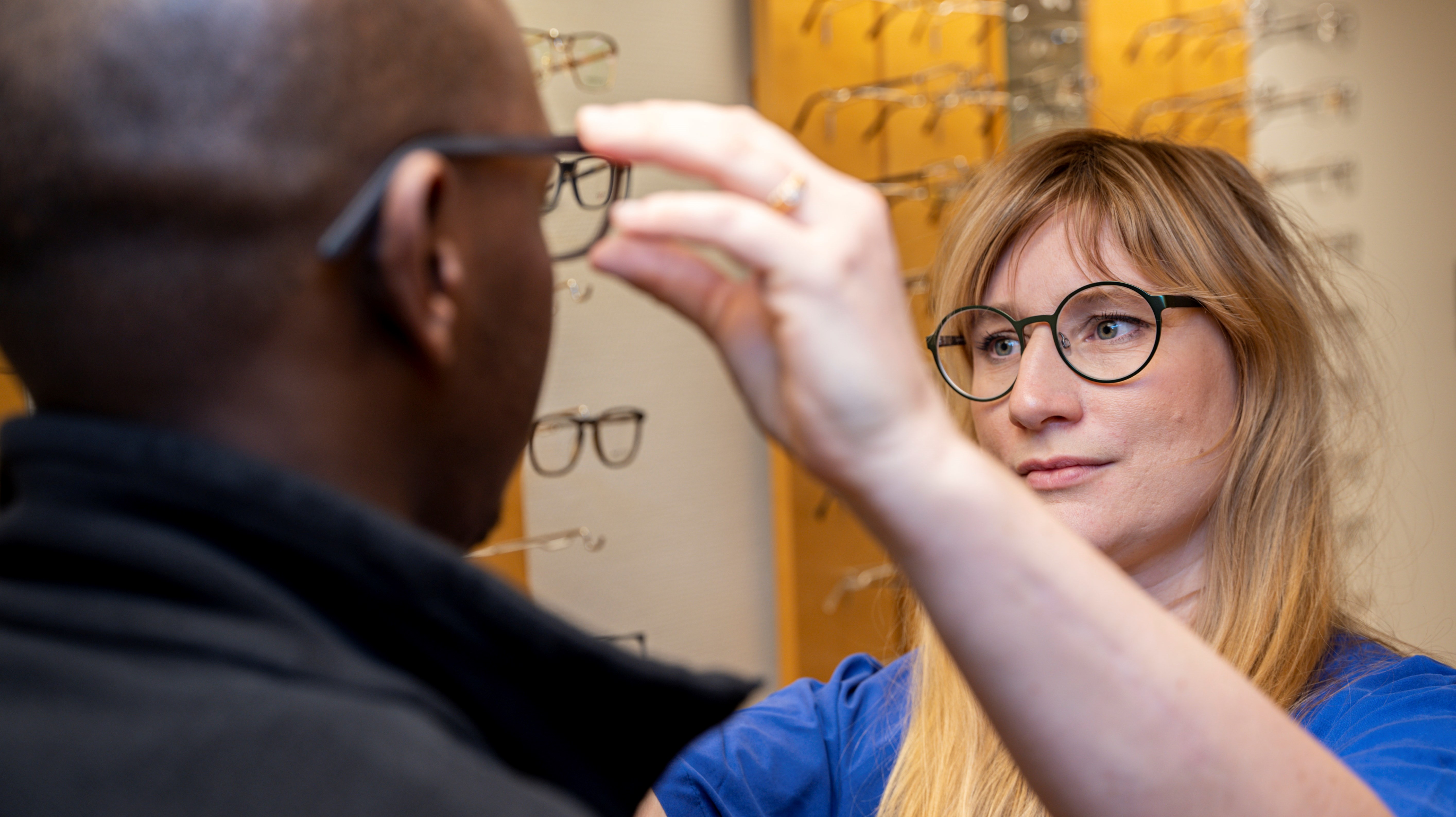 Behandlare provar ut glasögon på man. 