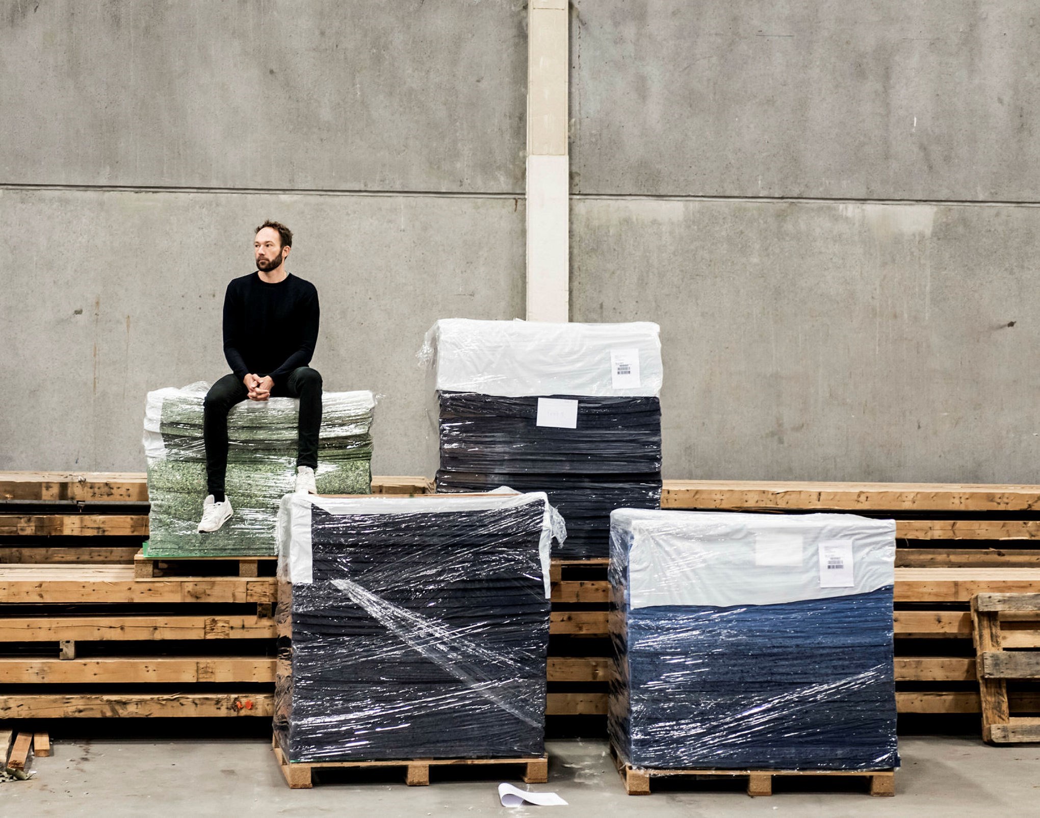 Anders Lendager sitter på en av flera pallar med återbrukat material.