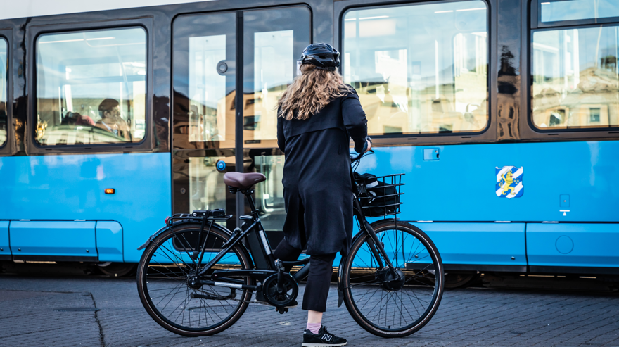 Cyklist står med sin cykel vid sidan av en spårvagn