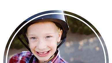 Ett leende barn med cykelhjälm.