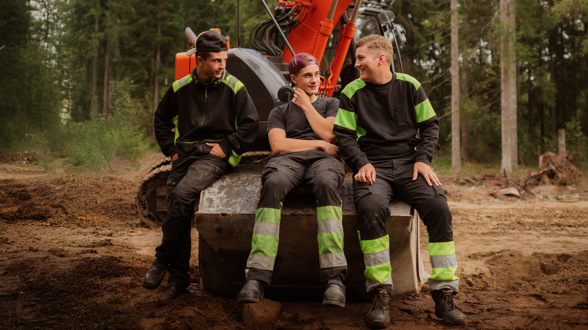 Tre elever sitter på grävskopa