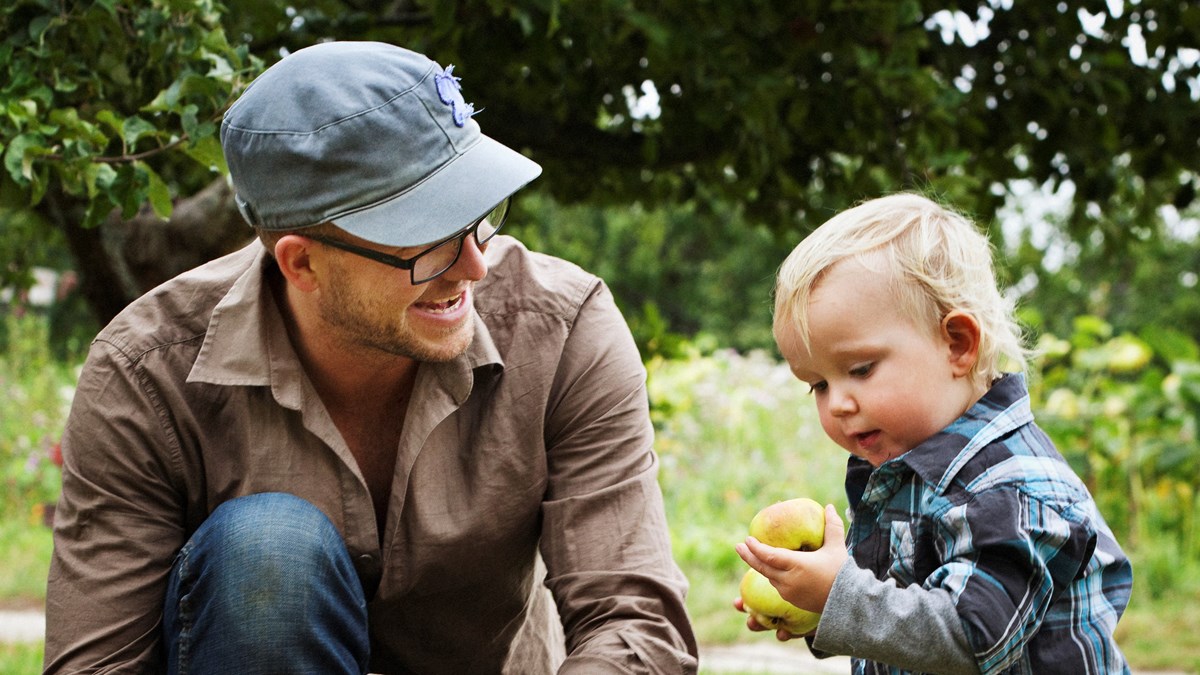 En vuxen man som tittar på ett barn som håller i ett äpple