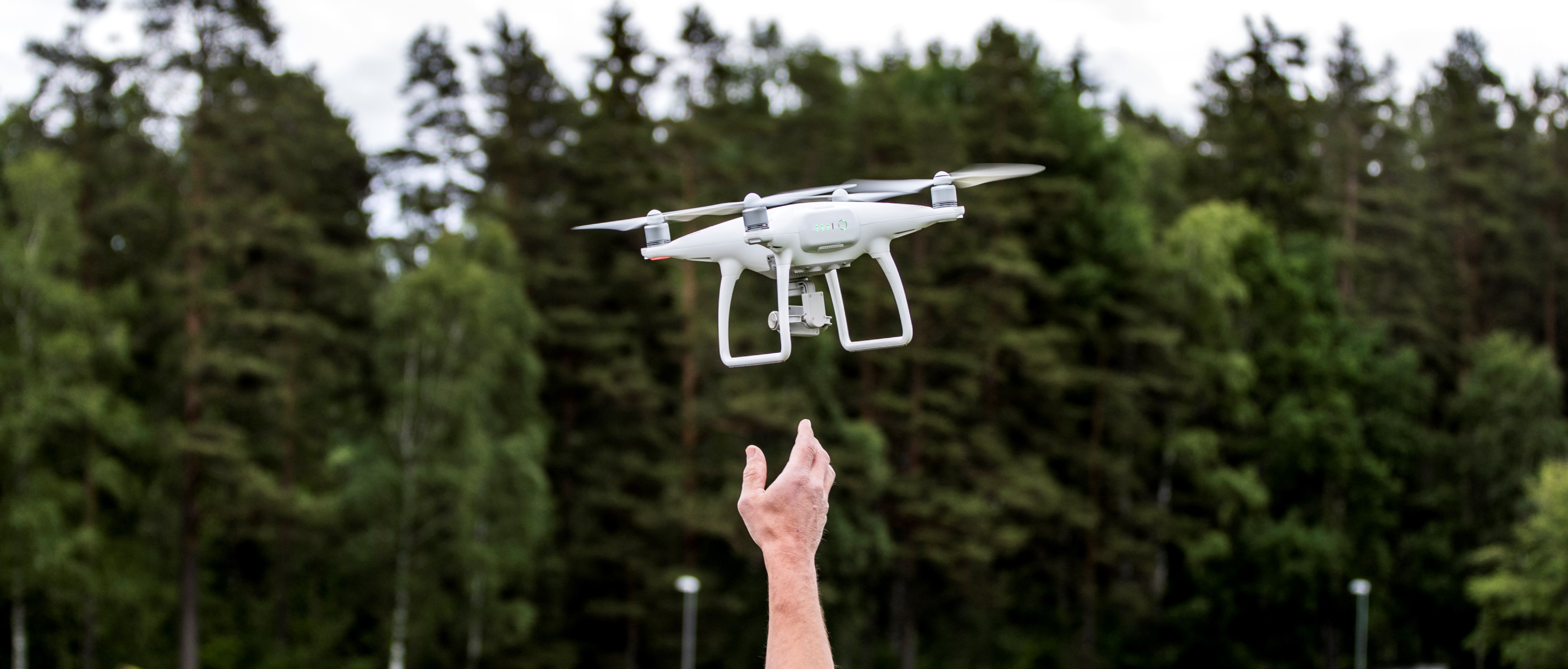 En hand sträcker sig upp för att nå en drönare i luften.
