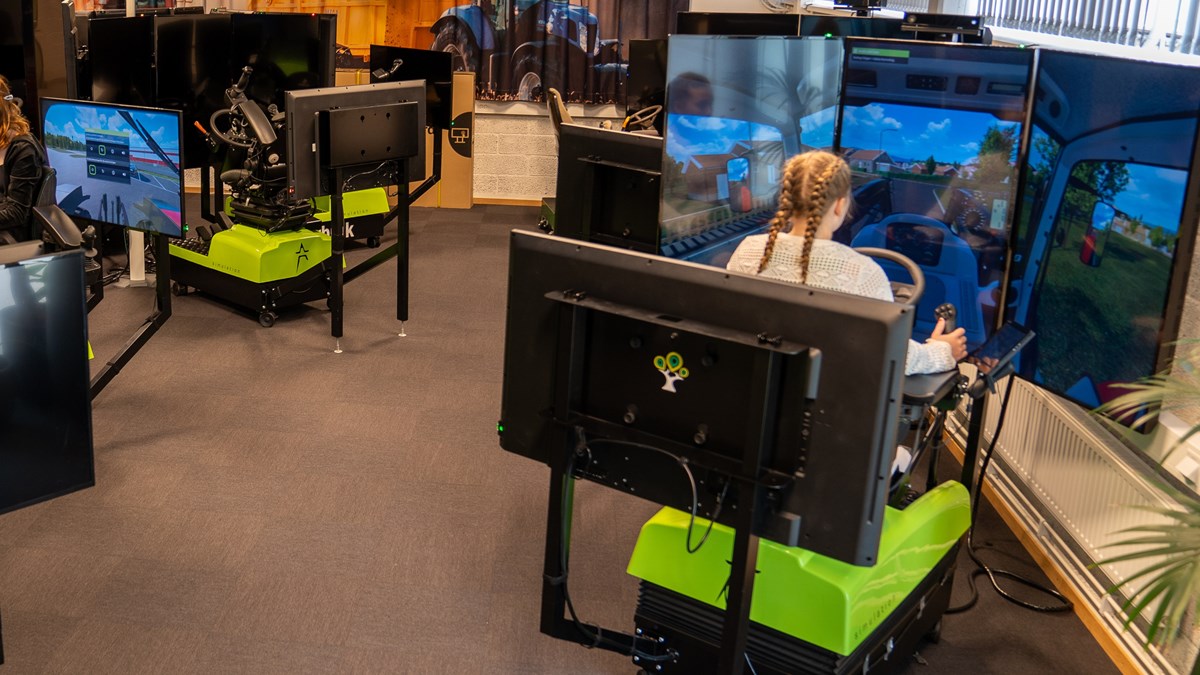 Elever sitter i simulatorer med skärmar och kör olika slags maskiner