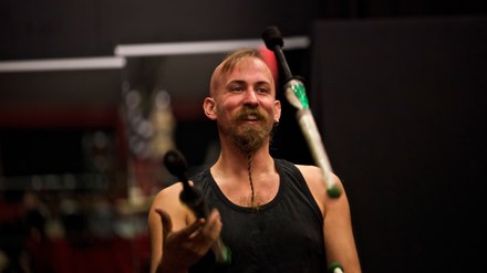 En glad man med skägg som jonglerar med släckta facklor.