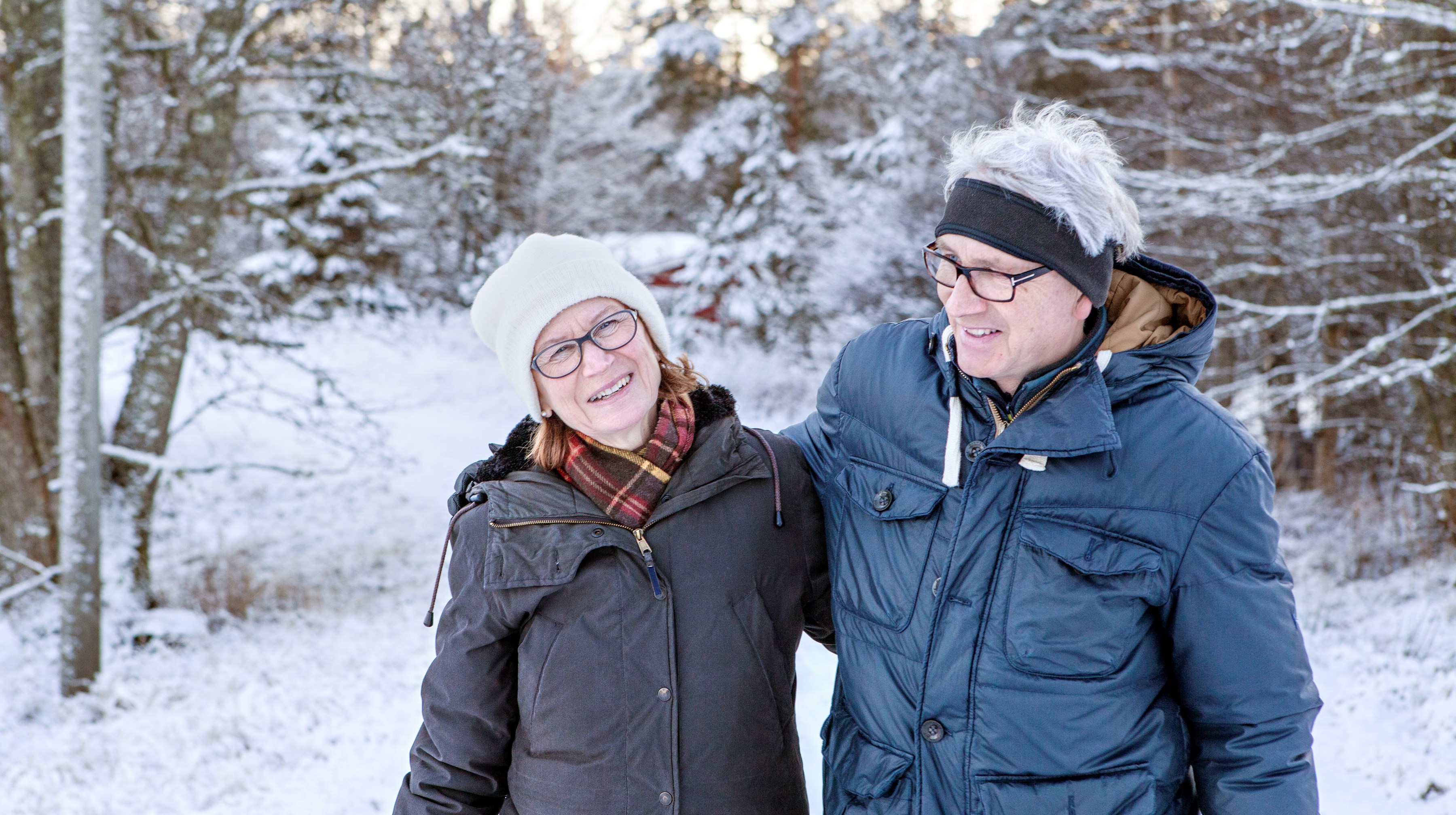 Pensionärspar framför snötäckta träd